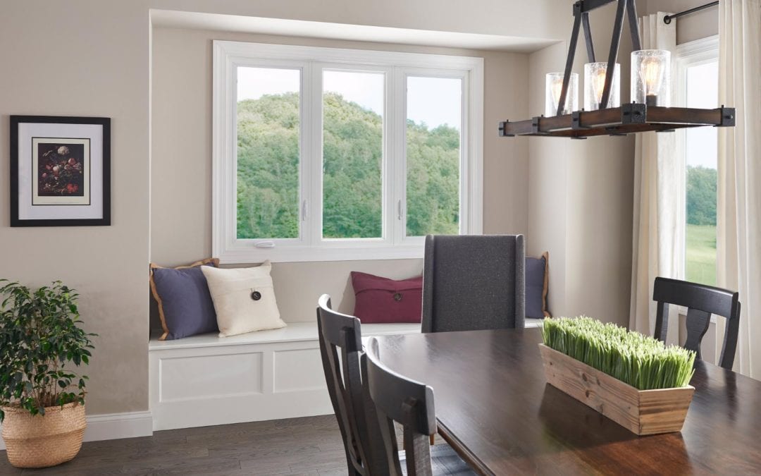 A stylish dining room with a dark wood table, farmhouse overhead light fixture and window seat with pillows.