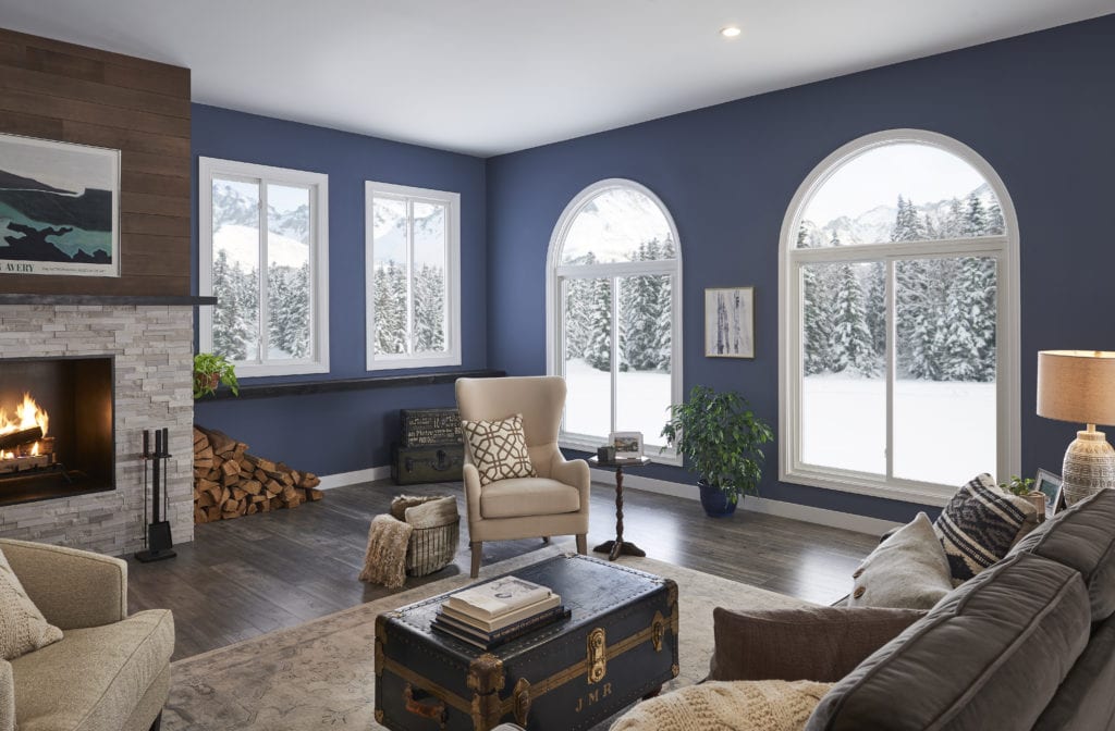 A beautiful living room with blue walls and a fireplace overlooking a snowy landscape.
